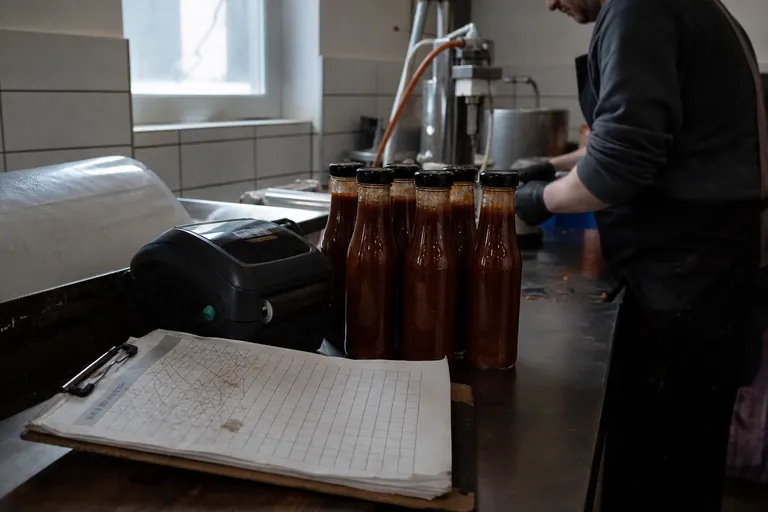 Checkliste, Etikettendrucker und abgefüllte Sauceflaschen in einer Manufaktur