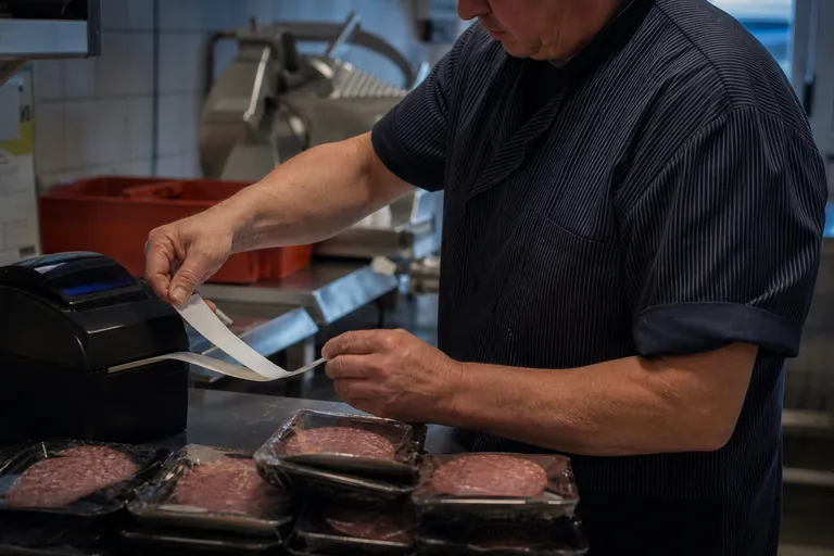 Mitarbeiter druckt Etiketten für verpackte Wurstschalen